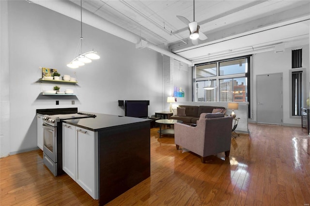 kitchen with pendant lighting, hardwood / wood-style flooring, ceiling fan, white cabinets, and stainless steel range oven