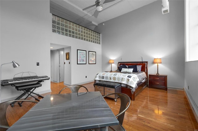 bedroom featuring ceiling fan, a towering ceiling, and light hardwood / wood-style floors