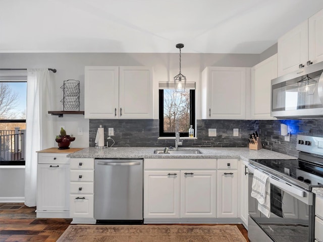 kitchen featuring sink, white cabinetry, decorative light fixtures, stainless steel appliances, and light stone countertops