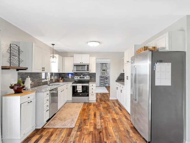 kitchen featuring sink, tasteful backsplash, decorative light fixtures, stainless steel appliances, and white cabinets