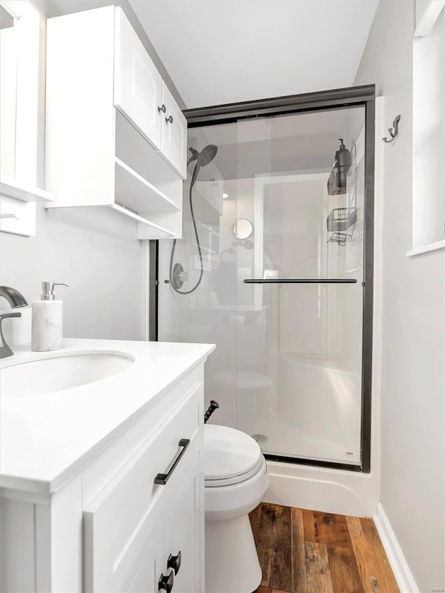 bathroom featuring vanity, toilet, a shower with shower door, and hardwood / wood-style floors