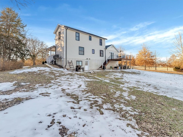 snow covered back of property with a wooden deck