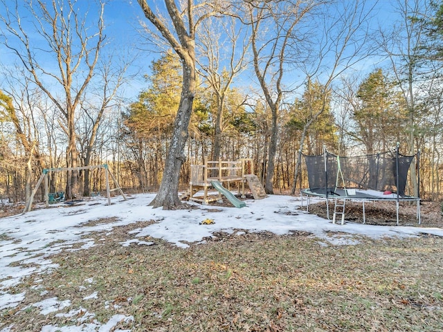 yard layered in snow with a playground and a trampoline