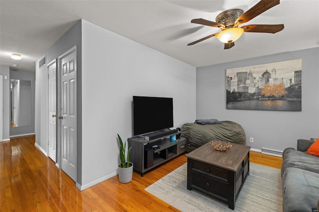 living room with wood-type flooring, a baseboard heating unit, and ceiling fan