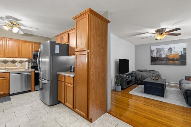 kitchen featuring light stone counters, light tile patterned floors, ceiling fan, stainless steel appliances, and backsplash