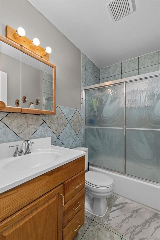 full bathroom featuring tile walls, vanity, toilet, and combined bath / shower with glass door