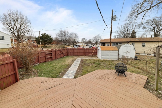 wooden deck featuring a storage shed, a fire pit, and a lawn