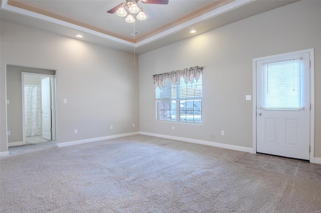 carpeted empty room featuring ceiling fan, a tray ceiling, and a high ceiling