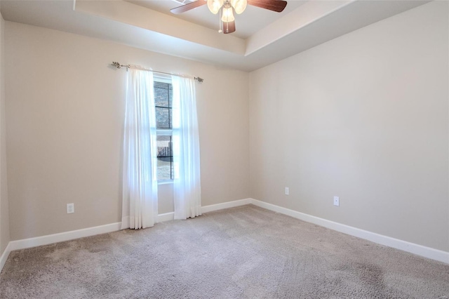 spare room with light carpet, ceiling fan, and a tray ceiling