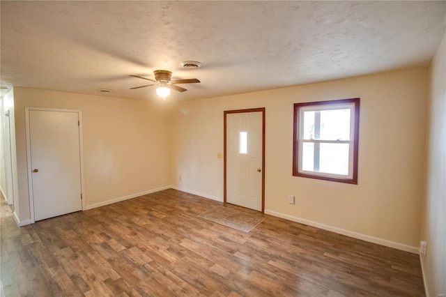 empty room featuring ceiling fan, wood-type flooring, and a textured ceiling