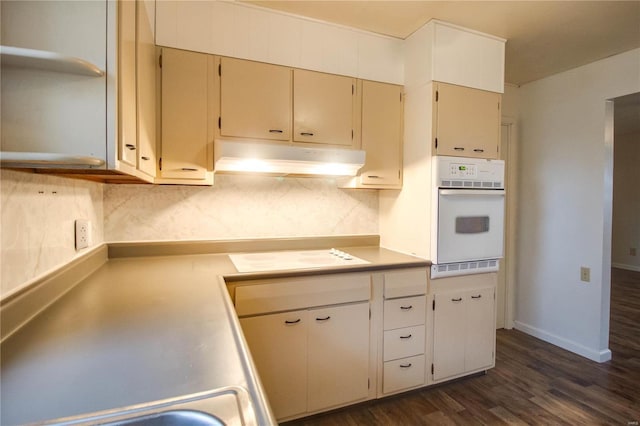 kitchen with dark wood-type flooring, white appliances, and decorative backsplash