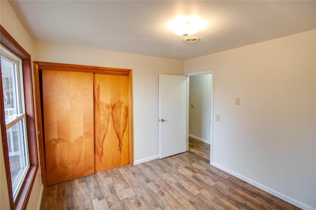 unfurnished bedroom featuring light hardwood / wood-style floors and a closet