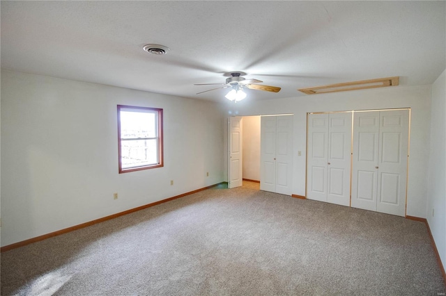 unfurnished bedroom featuring ceiling fan, multiple closets, and carpet