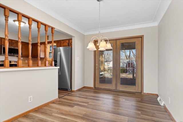 kitchen featuring tasteful backsplash, light wood-type flooring, a notable chandelier, pendant lighting, and stainless steel appliances