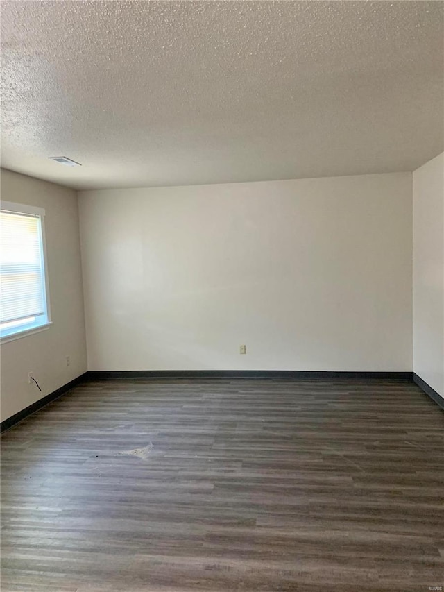 unfurnished room featuring dark hardwood / wood-style floors and a textured ceiling