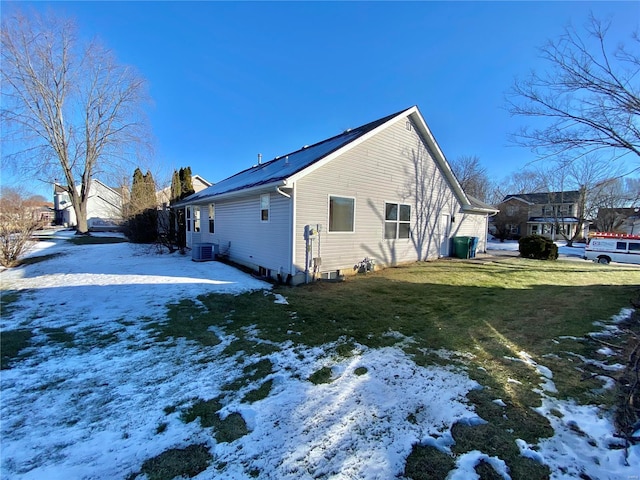 view of snow covered exterior with a yard and central AC