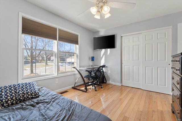 bedroom with light hardwood / wood-style flooring, ceiling fan, and a closet