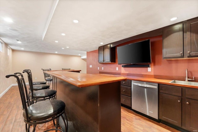 kitchen featuring wood counters, sink, stainless steel dishwasher, dark brown cabinetry, and light hardwood / wood-style floors