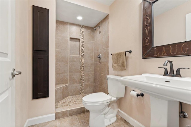 bathroom featuring tiled shower, tile patterned floors, and toilet