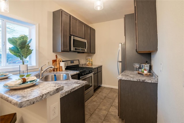 kitchen with appliances with stainless steel finishes, sink, dark brown cabinets, and kitchen peninsula