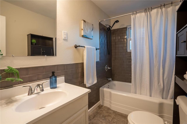 full bathroom with shower / tub combo with curtain, tile walls, tile patterned flooring, vanity, and toilet