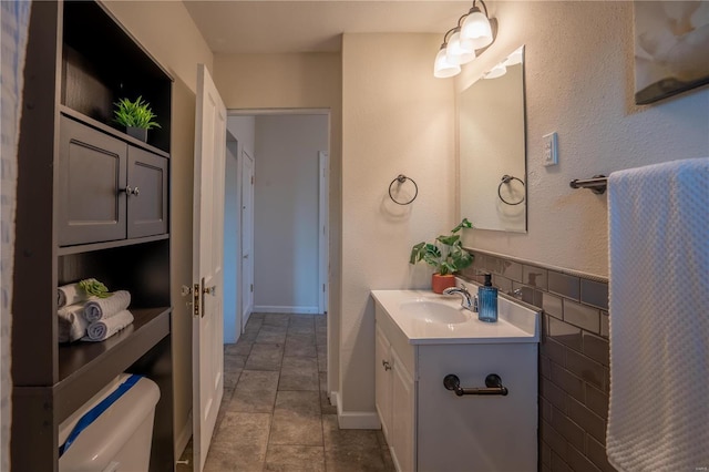 bathroom with vanity, tile patterned floors, tile walls, and toilet