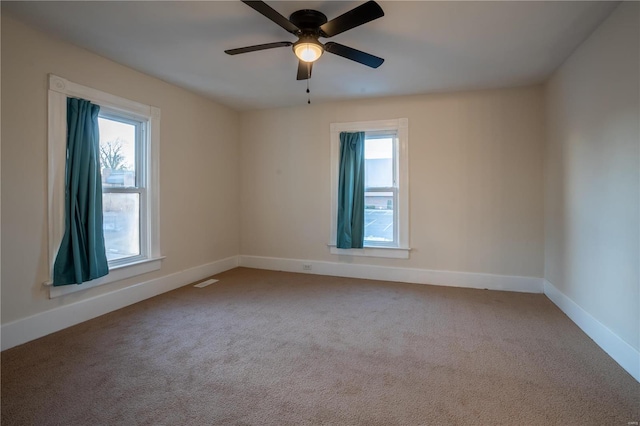 carpeted spare room with ceiling fan and plenty of natural light