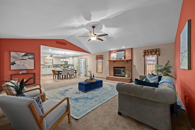 living room with lofted ceiling, ceiling fan with notable chandelier, a fireplace, and carpet floors