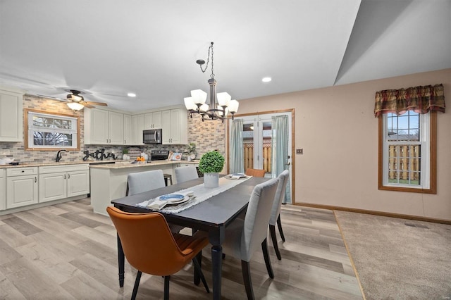 dining room with sink, ceiling fan with notable chandelier, and light hardwood / wood-style flooring