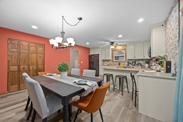 dining area featuring ceiling fan with notable chandelier and light wood-type flooring