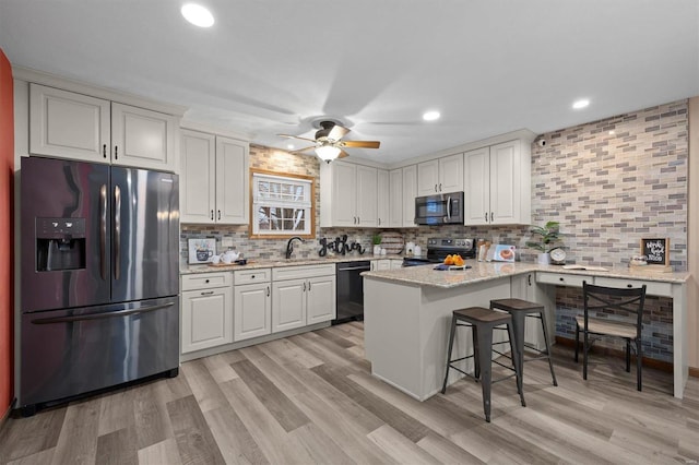 kitchen featuring white cabinetry, stainless steel appliances, a kitchen breakfast bar, and light stone counters