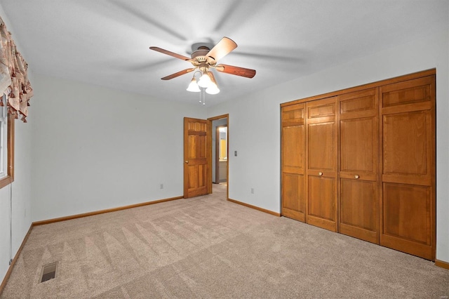 unfurnished bedroom with ceiling fan, a closet, and light carpet