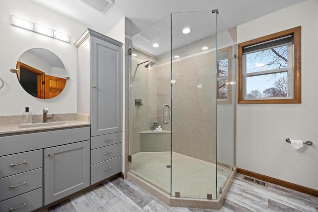 bathroom with wood-type flooring, a shower with shower door, and vanity