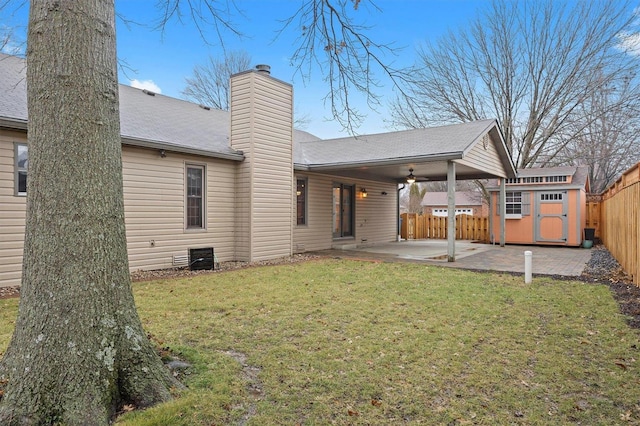 rear view of property with ceiling fan, a storage unit, a patio area, and a lawn