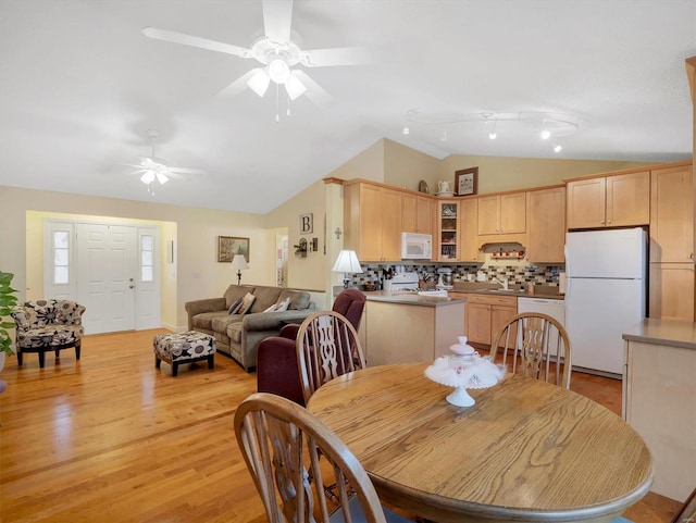 dining room featuring ceiling fan, lofted ceiling, sink, and light wood-type flooring