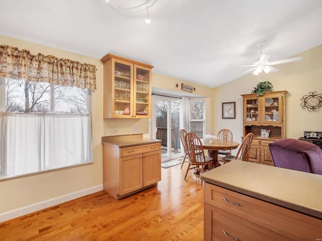 kitchen with vaulted ceiling, light brown cabinets, ceiling fan, and light hardwood / wood-style floors