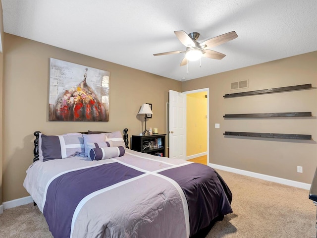 bedroom featuring a textured ceiling, light colored carpet, and ceiling fan