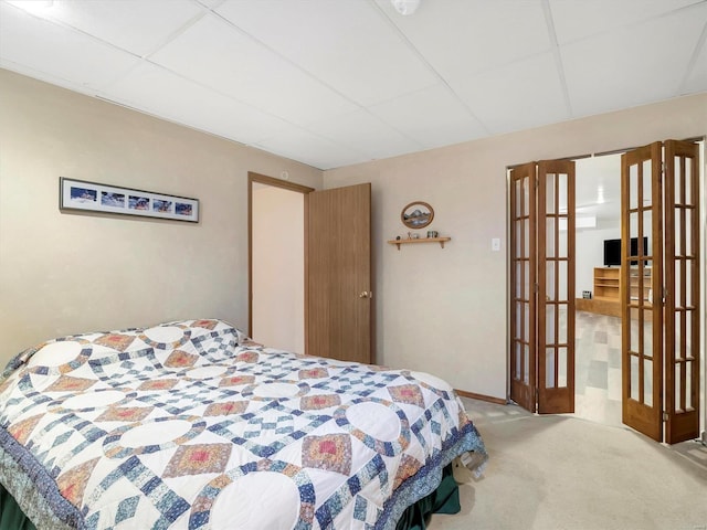 carpeted bedroom with a paneled ceiling and french doors