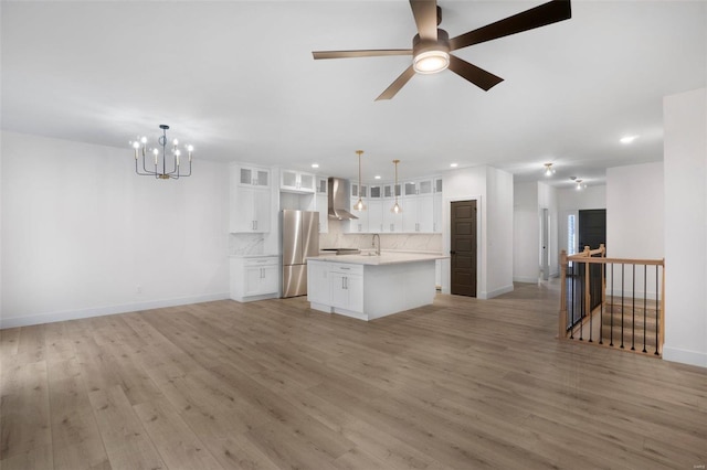 kitchen featuring decorative light fixtures, tasteful backsplash, white cabinetry, a center island, and wall chimney exhaust hood