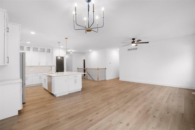 kitchen featuring white cabinetry, tasteful backsplash, decorative light fixtures, a center island with sink, and appliances with stainless steel finishes