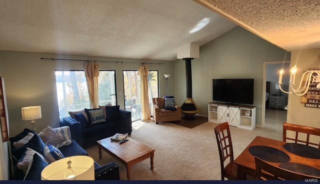 living room with lofted ceiling, light carpet, a textured ceiling, and a wood stove