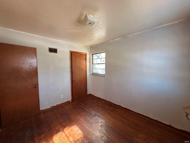 unfurnished bedroom featuring dark hardwood / wood-style flooring and a closet