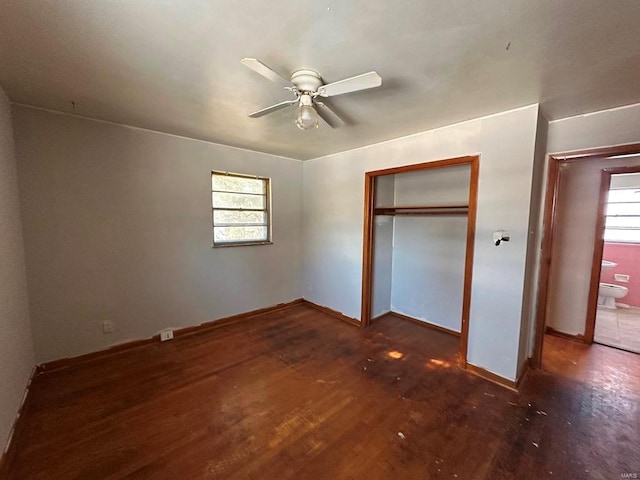 unfurnished bedroom with dark wood-type flooring, ceiling fan, multiple windows, and a closet