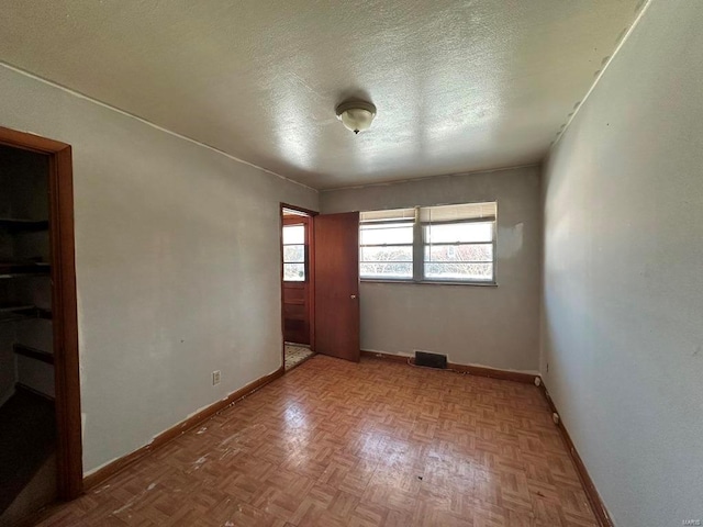 spare room with light parquet flooring and a textured ceiling