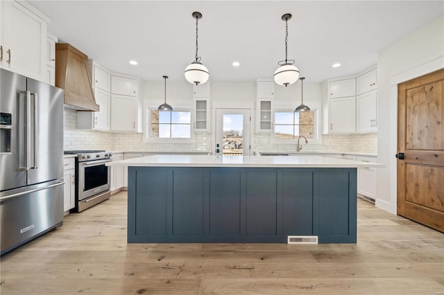 kitchen with white cabinets, a center island, hanging light fixtures, and premium appliances