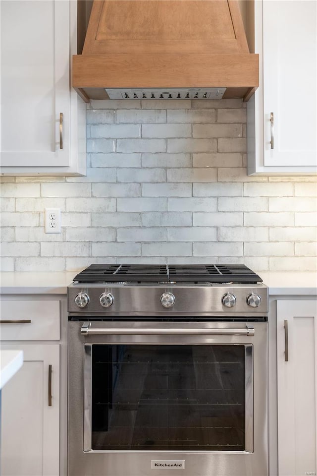 kitchen with tasteful backsplash, stainless steel gas range, custom exhaust hood, and white cabinets