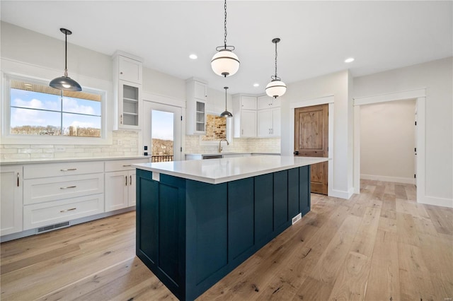 kitchen featuring white cabinetry, a center island, light hardwood / wood-style floors, and tasteful backsplash