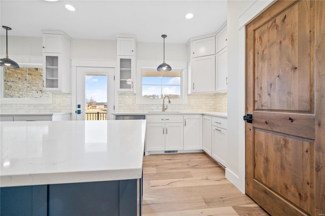 kitchen with sink, pendant lighting, white cabinets, and backsplash