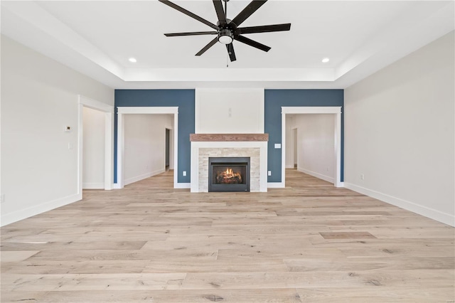 unfurnished living room with baseboards, a raised ceiling, and recessed lighting