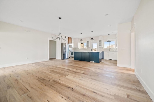 kitchen featuring light wood-style flooring, stainless steel appliances, decorative backsplash, and a center island